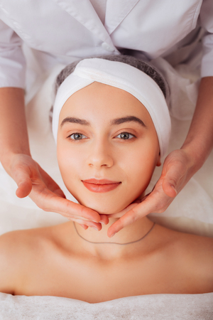 Beginning of the massage. Soft female hands touching the clients chin while beginning the procedure of the massageの写真素材