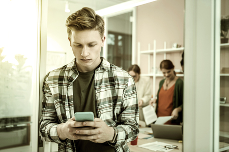 Break from class. Handsome blonde-haired student using his phone during break from classの写真素材