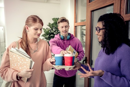 Break together. Three best friends wearing colorful sweatshirts enjoying their coffee break togetherの写真素材