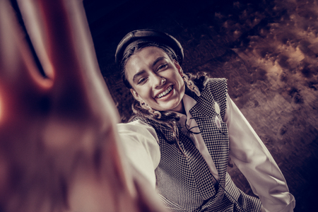 Beautiful smile. Joyful happy woman smiling into the camera while taking in into her handの写真素材