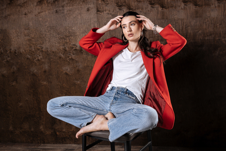 Beautiful look. Nice thoughtful woman posing for a photo while sitting on the chairの写真素材