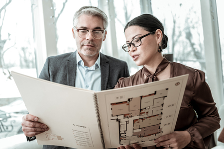 Busy day. Dark-haired elegant woman wearing a brown satin blouse and her business partner looking busyの写真素材