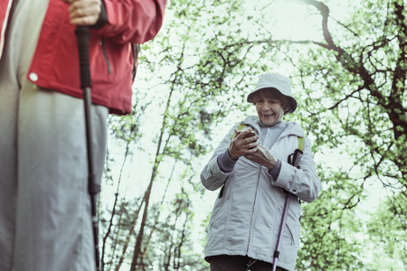 Hiking and gadgets. An elderly woman sharing her hiking experience by texting with relativesの写真素材