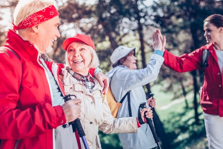 Hugging wife. Bearded retired man hugging his lovely appealing lady while Nordic walking togetherの写真素材