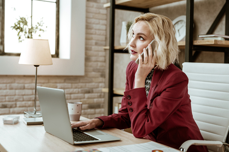 Aggressively talking. Unpleasant short-haired businesswoman rolling her eyes during conversation about affairs and businessの写真素材