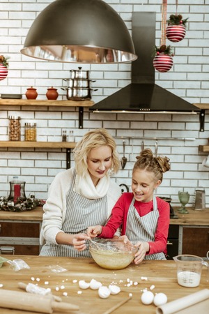 Entertaining themselves. Accurate appealing adult lady in white sweater transmitting whisk to...