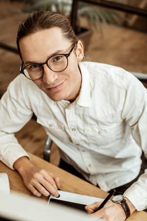 Diligent worker. Top view of a nice hard working man smiling while using a drawing tabletの写真素材