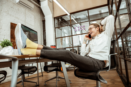 Phone call. Positive joyful man smiling while having a pleasant conversationの写真素材
