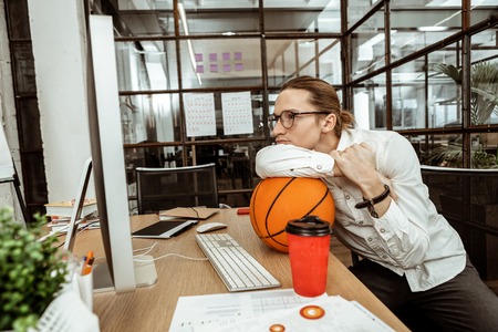 Office routine. Nice bored man sitting with a ball while wanting to rest from workの写真素材