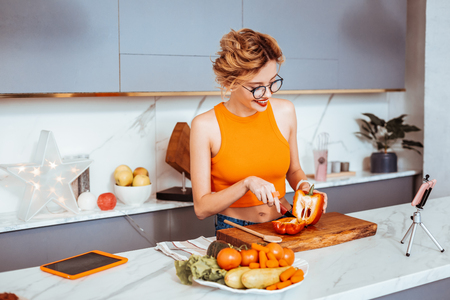 Salad preparation. Nice slim woman cutting a red pepper while preparing a salad for herselfの写真素材