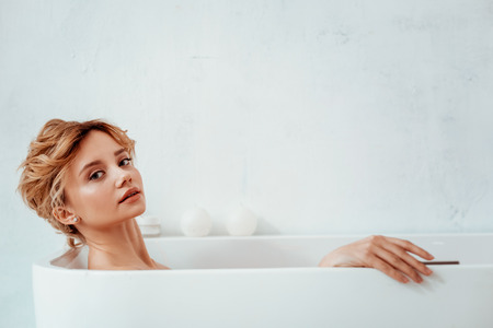 Absolute relaxation. Delighted young woman feeling relaxed while enjoying her time in the bathtubの写真素材