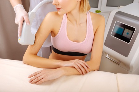 Depilatory specialist. Slim young woman visiting experienced depilatory specialist for arm depilationの写真素材