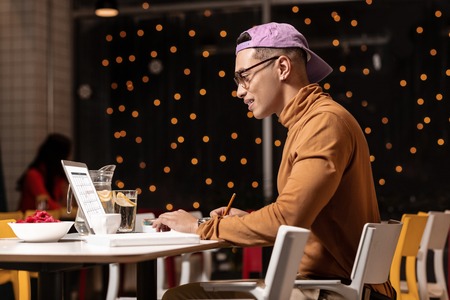 Before dinner. Good-looking smart guy working in restaurant with job laptop and waiting for his big...