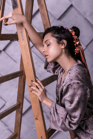 Spring campaign shooting. Profile portrait photo of dazzling elegant brunette displaying stylish hairdo with bright silk printed scarf amid spring campaign shootingの写真素材