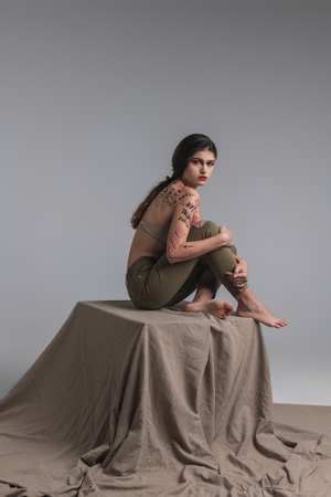 Flexible model. Long-haired cute young model with body art wearing a beige bra looking flexibleの写真素材