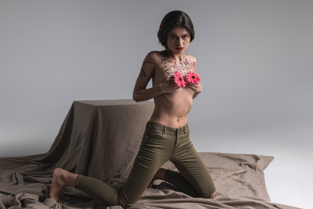 Photoshoot for a magazine. Young brunette pretty half-naked model wearing tight jeans looking brassilyの写真素材