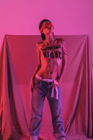 Proud looks. Young dark-haired cute naked blindfolded model wearing a blindfold raising her headの写真素材