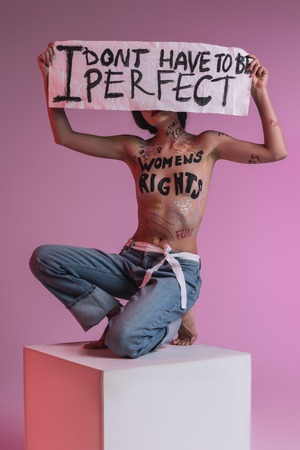 Closing a face. Young brunette pretty half-naked model wearing blue jeans closing her face with the bannerの写真素材