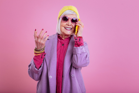 Loving pink color. Fashionable modern elderly lady loving pink color calling her caring husbandの写真素材