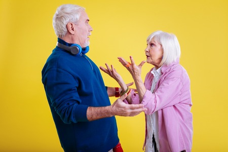 Emotional conversation. Couple of fashionable cute pensioners having extremely emotional conversationの写真素材