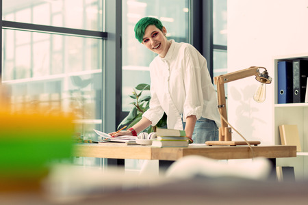 My start up. Nice good looking woman smiling while working on her own projectの写真素材