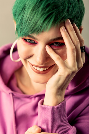 Pleasurable mood. Portrait of a cheerful short haired woman smiling while touching her faceの写真素材