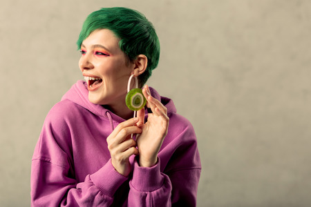Great match. Nice green haired woman smiling while touching a green lollipopの写真素材