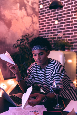 Another attempt. Thin attentive man looking for schemes to create paper planes on the Internet, completely distracted from important work.の写真素材