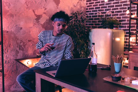 Doing training. Relaxed attractive African American boy trying to pass difficult online training...