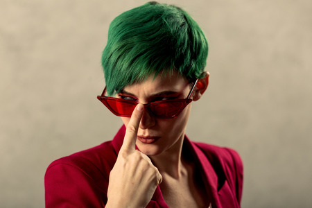 Serious look. Portrait of an attractive serious woman while fixing her sunglassesの写真素材