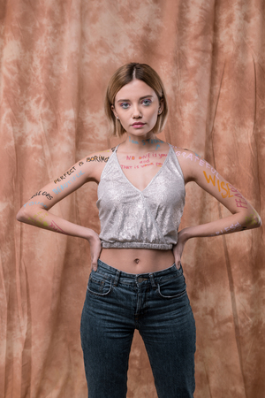 Social movement. Beautiful nice woman looking at you while having inscriptions on her bodyの写真素材