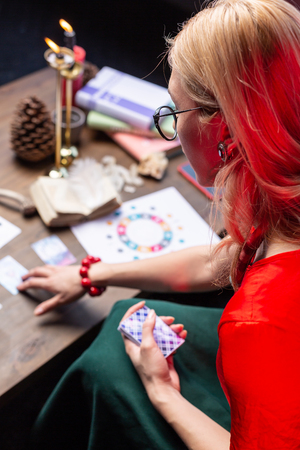 Astrologist practicing. Top view of female blonde-haired experienced astrologist sitting at the table and practicingの写真素材