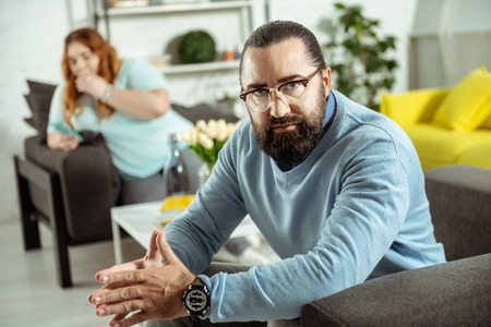 Join me. Serious bearded man looking straight at camera and holding hands togetherの写真素材