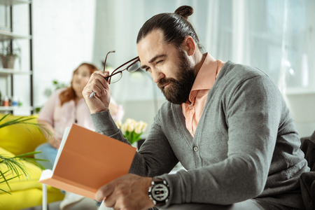 Cannot read. Serious man squinting while reading plans for dayの写真素材