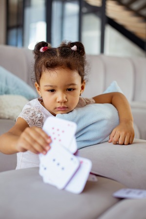 Little gamer. Serious child pressing lips while standing near sofa