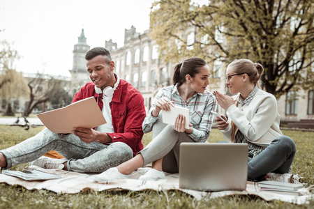Girls secrets. Cheerful females spending time in park while preparing for examinationの写真素材