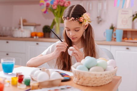 Relaxed atmosphere. Attentive girl bowing head while looking at her resultの写真素材