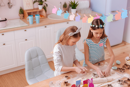 Join us. Serious brunette kid bowing head while taking iron form for bakingの写真素材