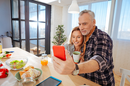 Sitting in kitchen. Mature couple of businessmen posing for photo while sitting in the kitchenの写真素材