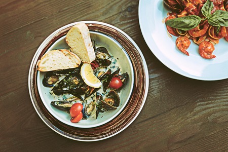 Expensive meals. Juicy good-looking seafood meals standing nearby on wooden table and having seafood insideの写真素材