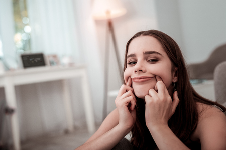 False smile. An upset teenager girl trying to make a smileの写真素材