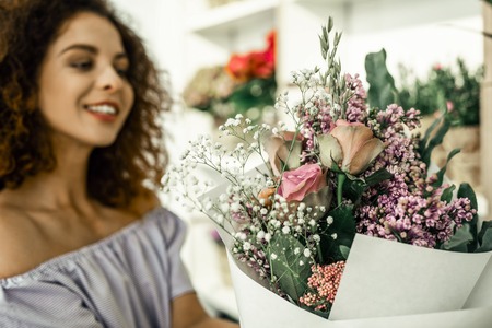 Beautiful bouquet. Cheerful woman feeling amazing after making beautiful bouquet for client while working in flower shopの写真素材