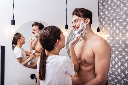 Nice sexy abs. Handsome husband with nice sexy abs hugging wife putting shaving foam on his faceの写真素材