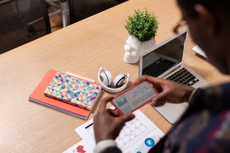 Verifying the information. A man checking the information on paper with his smartphone