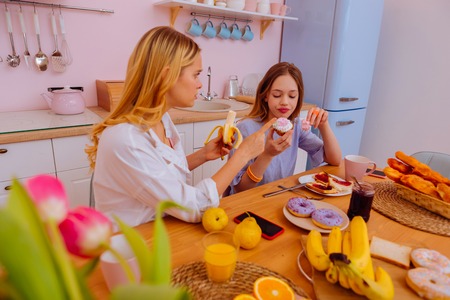 About healthy diet. Caring older sister with blonde curly hair telling her sibling about healthy dietの写真素材