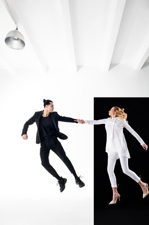 In spacious room. Two good-looking creative models in white and black suit posing in spacious roomの写真素材