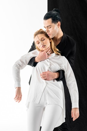 Woman in hands. Dark-haired model with hair bun holding tender young woman in hands while posing