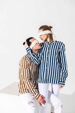 Touching head. Blonde-haired model touching head of her handsome colleague while wearing blindfoldsの写真素材
