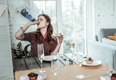 Drinking the spirit. A woman drinking champagne from the bottle on her birthdayの写真素材
