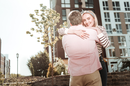 In love. Positive young woman smiling while hugging her husbandの写真素材
